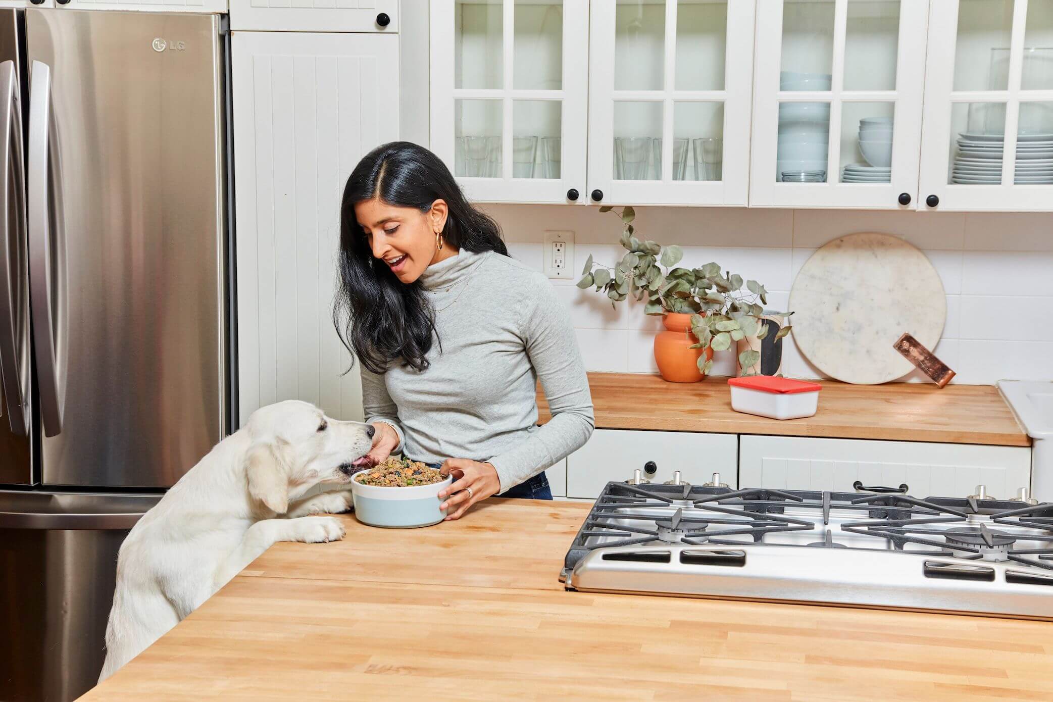 woman-feeds-her-white-dog-from-counter-in-crisp-white-kitchen-1-