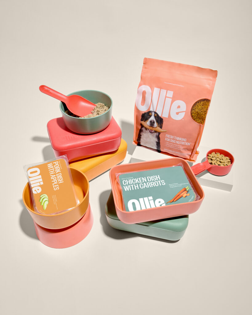 Variety of Ollie products on tan background with Puptainer, scoop, and bowls